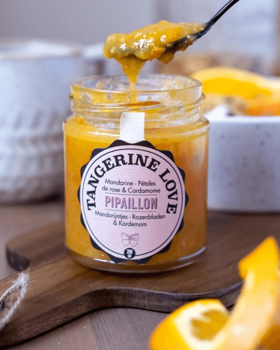 Offenes Glas Pipaillon Bio-Konfitüre "Tangerine Love" in leuchtendem Orange, ein Löffel hebt die Marmelade heraus.