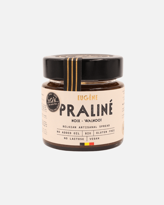 Praliné Walnussbutter von Eugène Chocolatier in einem Glas mit beigem Etikett, schwarzem Deckel und goldener Verzierung.