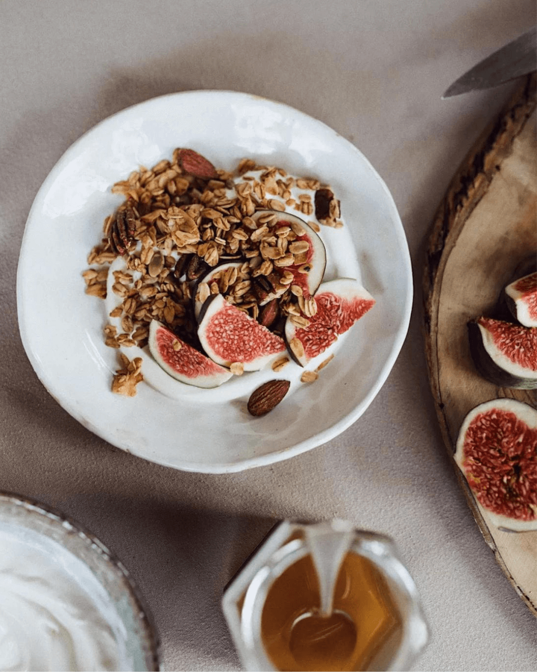 Ein Teller mit Joghurt, Bamboo Breakfast Granola mit karamellisierten Mandeln und Pekannüssen, verfeinert mit frischen Feigen.