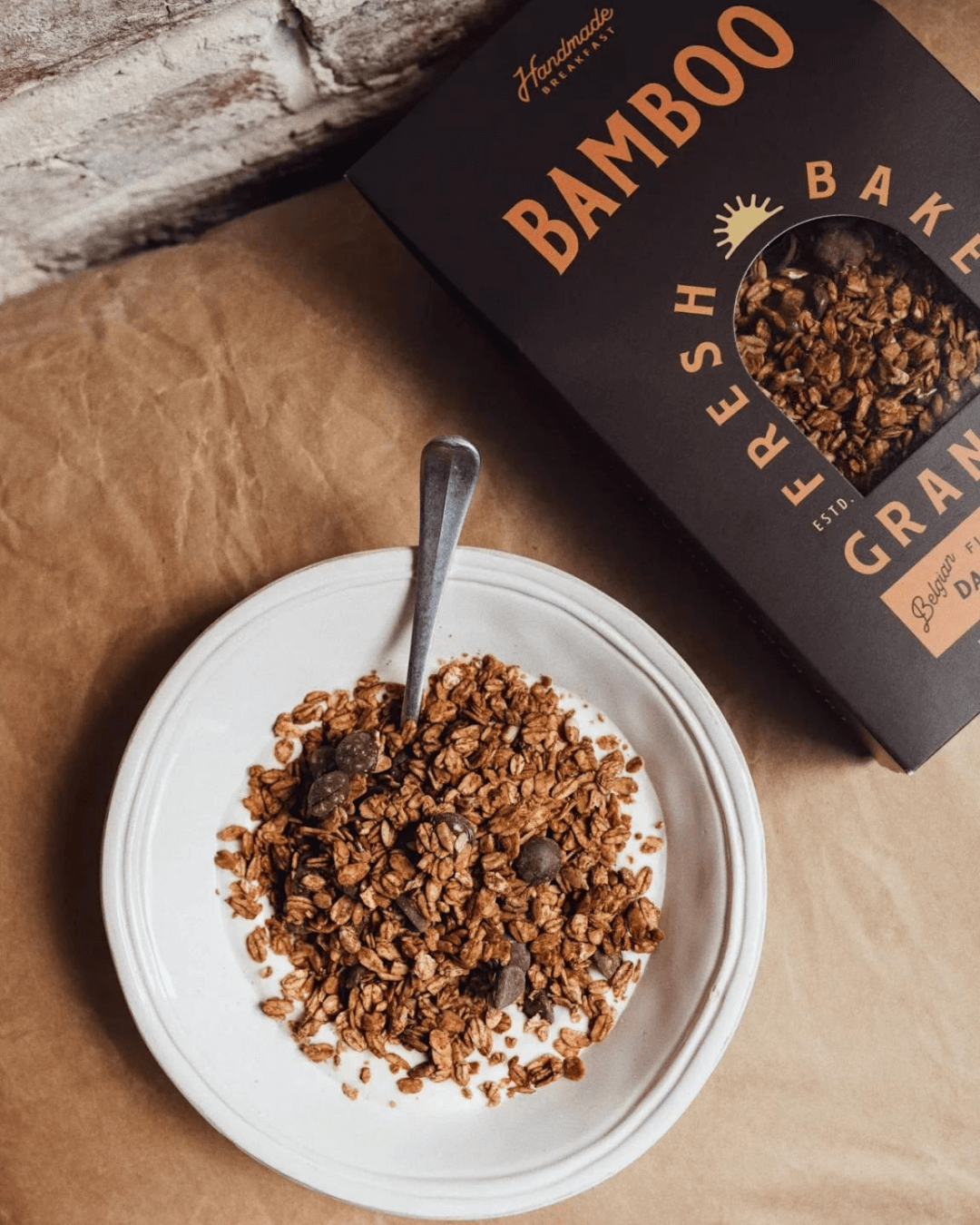 Eine Schale mit Bamboo Breakfast Granola mit Zartbitterschokolade und Fleur de Sel, daneben die passende Verpackung.