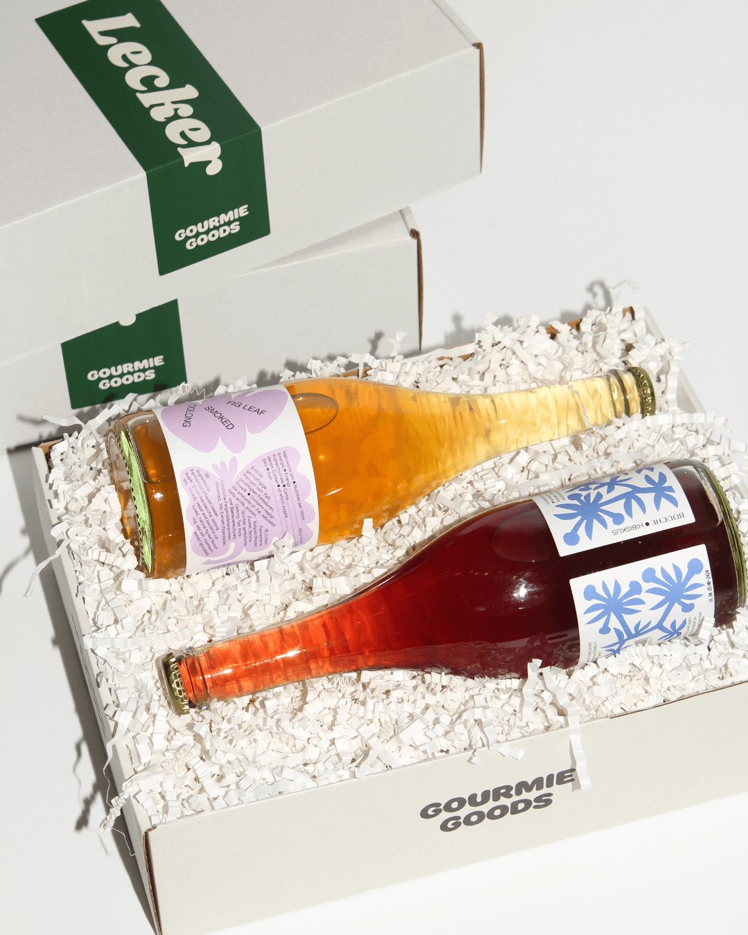Geschenkbox mit zwei Flaschen Bouche alkoholfreier Getränke in einer Gourmie Goods-Box, umgeben von weiteren Geschenkboxen.