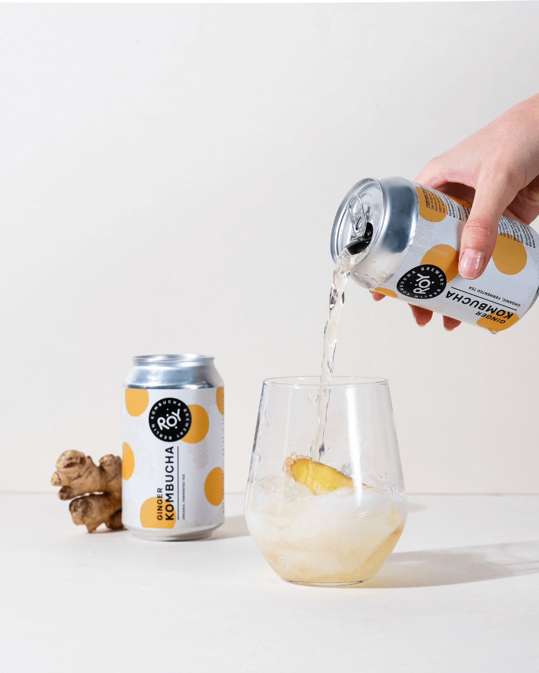 Eine Person gießt einen ROY Kombucha mit Ingwer in ein Glas.