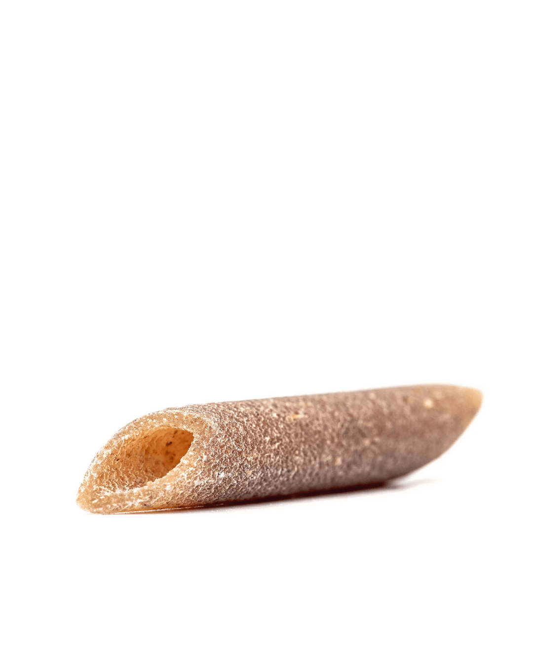 Detailaufnahme einer einzelnen Bio Penne Lisce Turanici von Mancini mit glatter Oberfläche und schrägem Schnitt, aus Urweizen in Bio-Qualität.