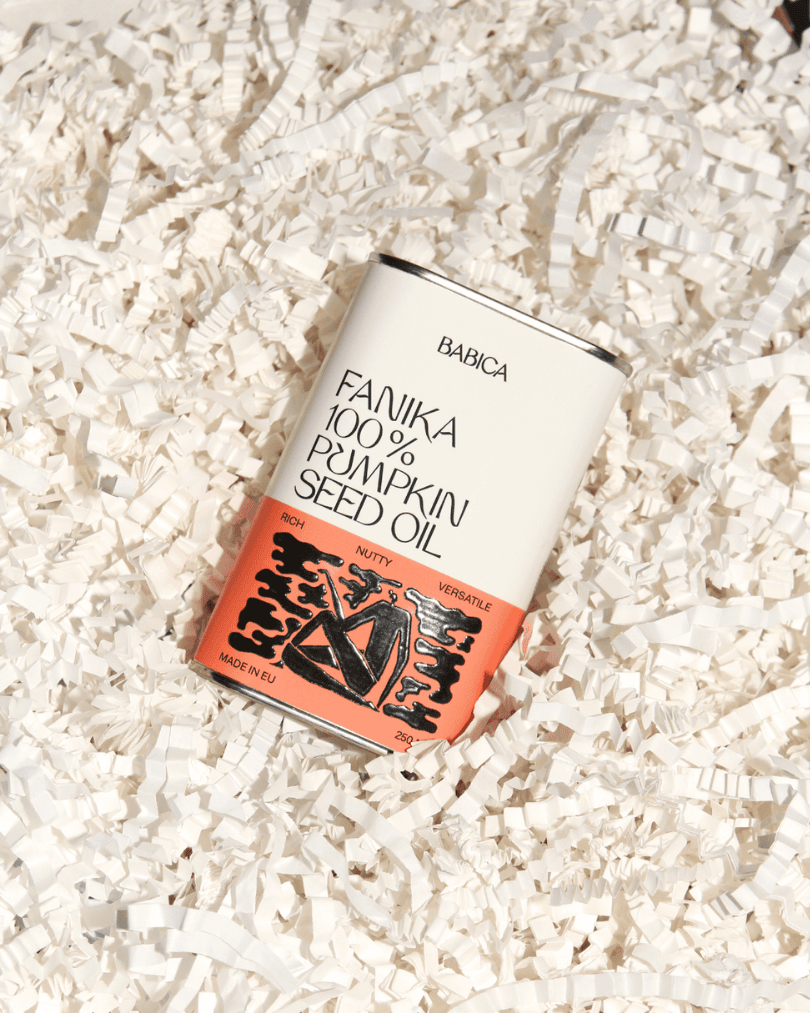Fanika Kürbiskernöl in einer weißen Verpackung mit orangefarbenem Design, präsentiert auf weißem Füllmaterial.