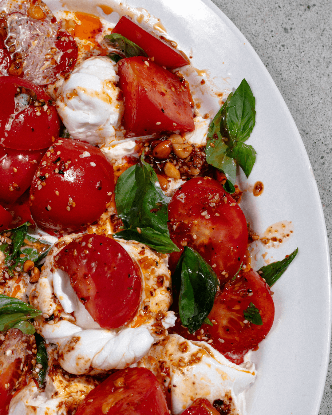 Tomaten-Burrata-Salat mit Chiliöl und frischem Basilikum.