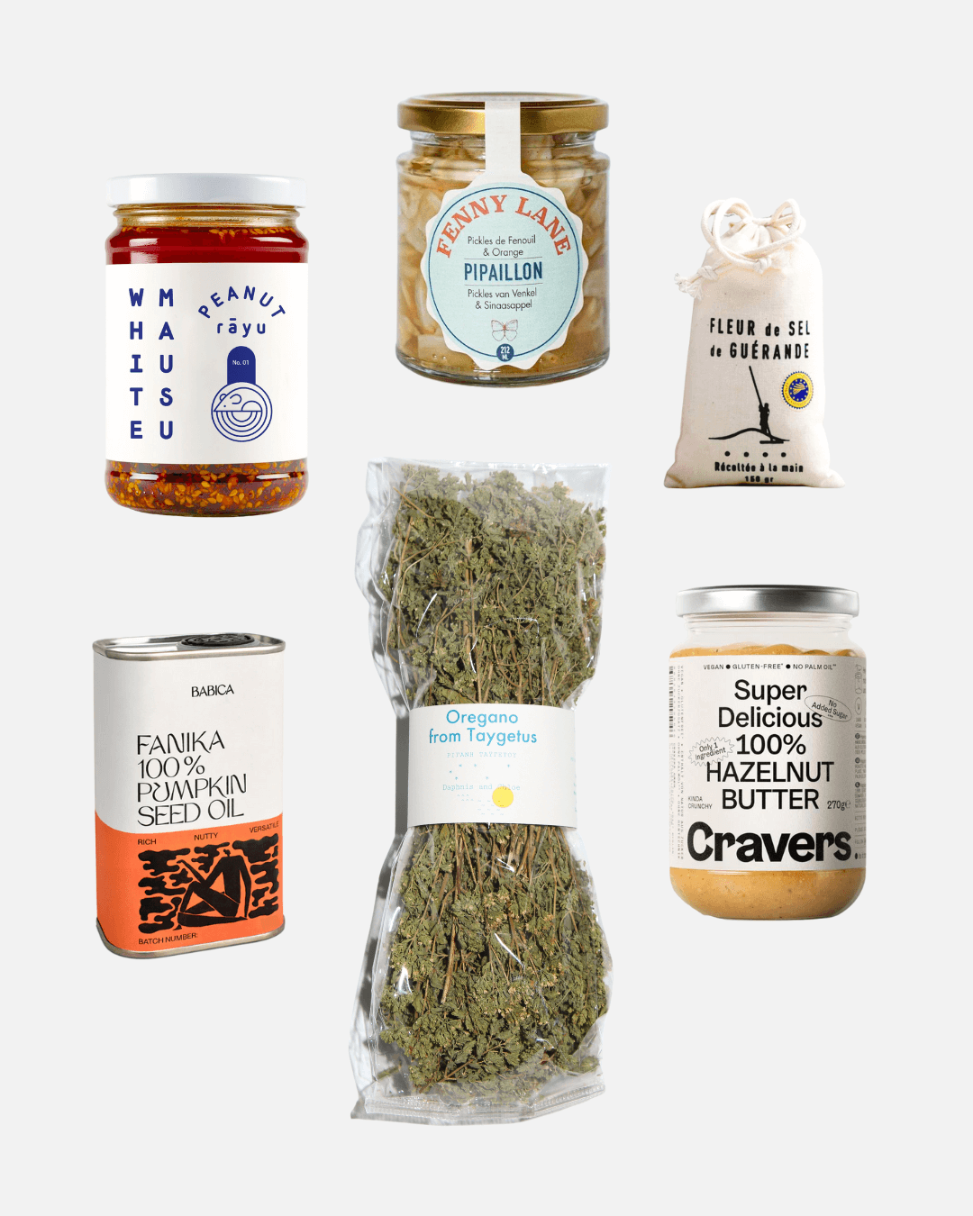 Sammlung von Gourmet-Lebensmitteln, darunter Erdnuss-Rayu, Pickles, Oregano, Kürbiskernöl, Fleur de Sel und Haselnussbutter.
