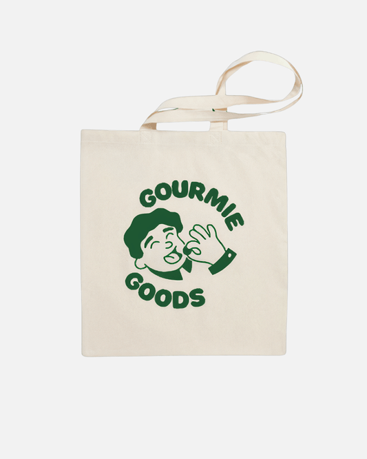 Baumwoll-Tragetasche mit grünem "Gourmie Goods"-Logo und einem Genießer-Motiv in der Mitte.