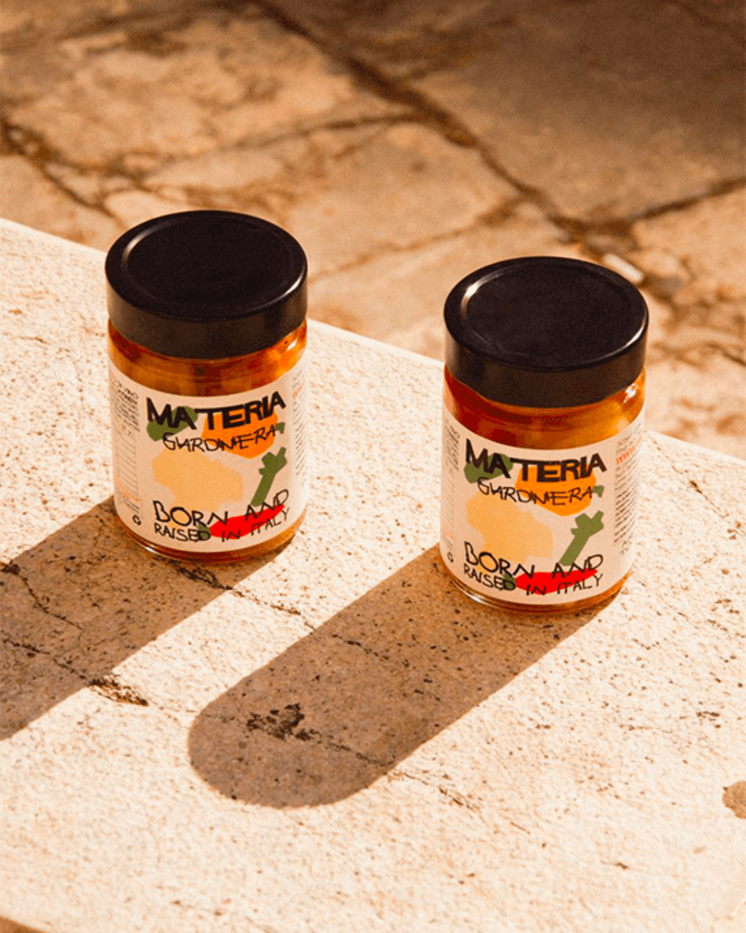 Zwei Gläser Materia Giardiniera, eingelegtes Gemüse aus Italien, stilvoll in warmem Sonnenlicht inszeniert.