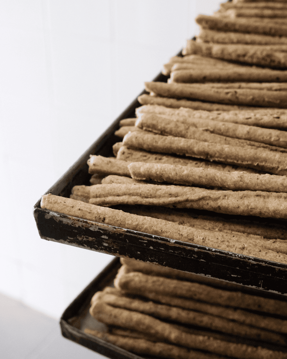 Frisch gebackene Bio-Brotstangen auf stapelbaren Backblechen in einer Bäckerei, bereit zum Abkühlen.