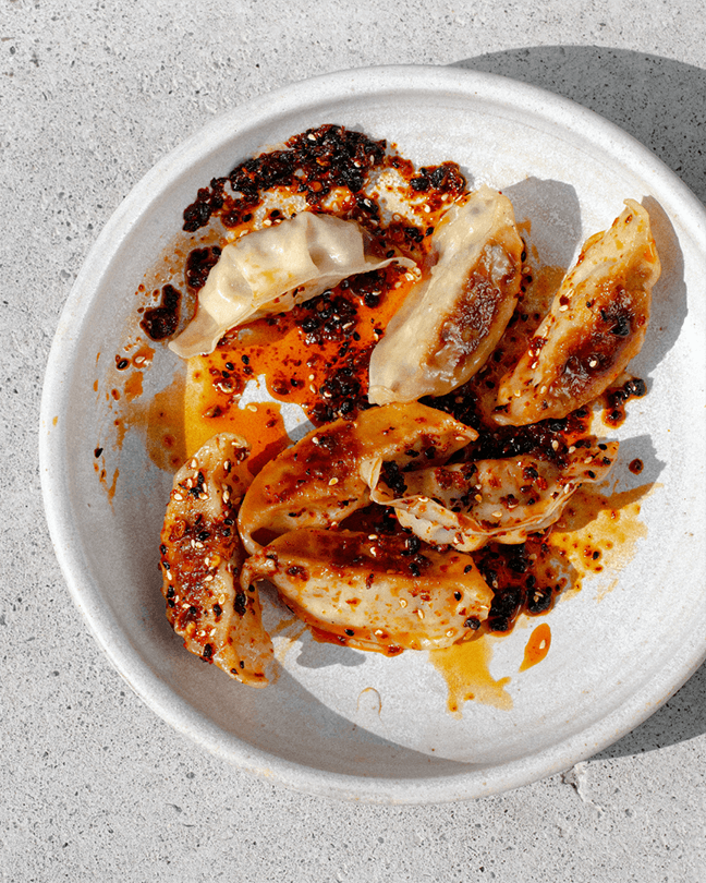 Gyoza mit White Mausu Black Bean Rayu auf einem Teller.