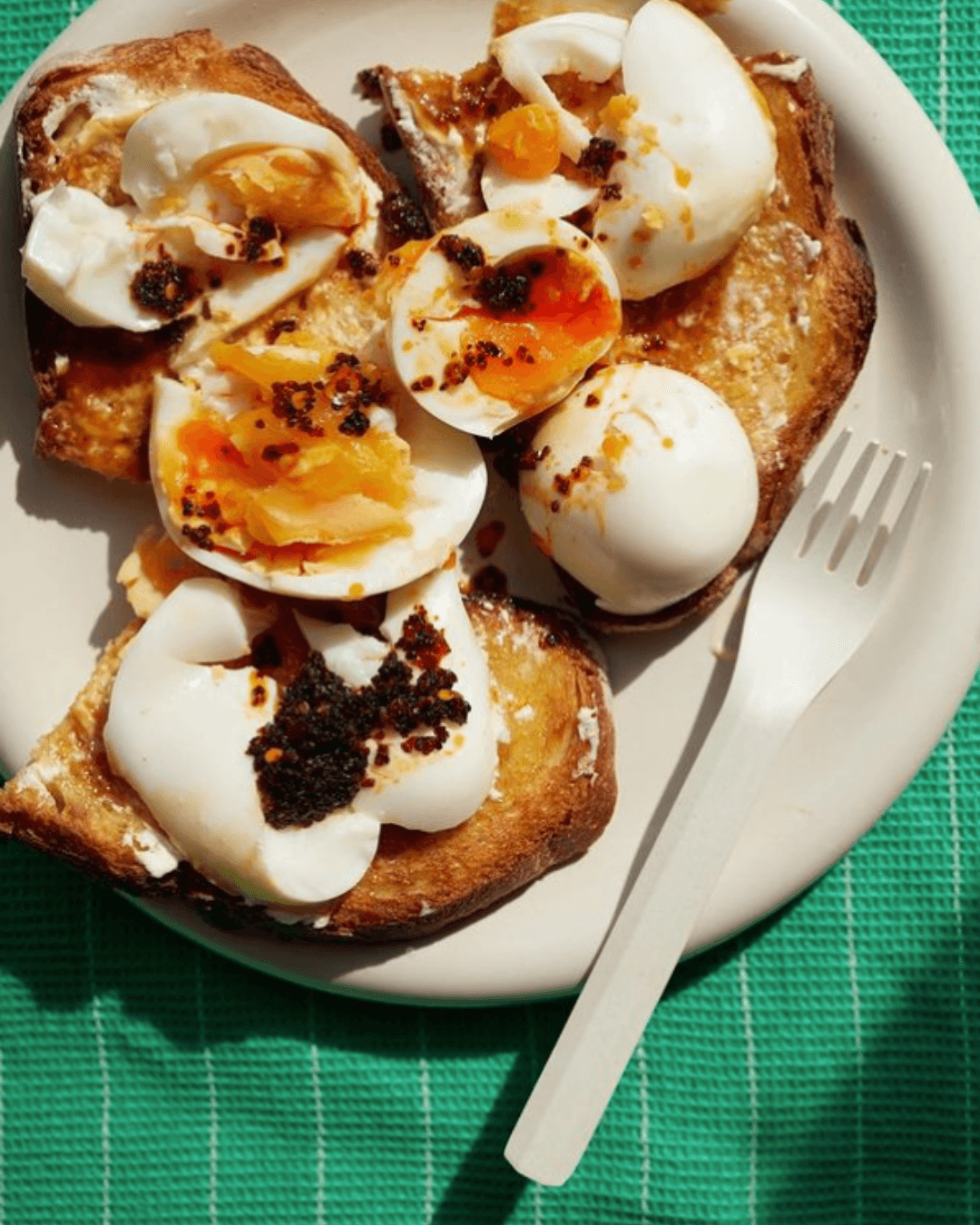 Geröstetes Brot mit weichen Eiern und knusprigem Chili-Topping von White Mausu, serviert auf Teller.