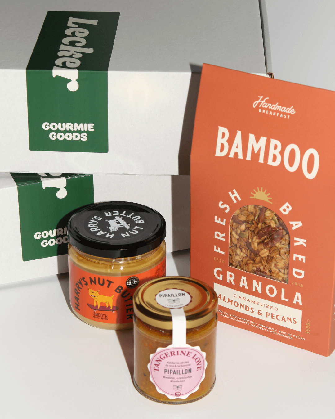 Produkte aus der „Breakfast in Bed“-Geschenkbox von Gourmie Goods, arrangiert vor der weißen Geschenkbox.