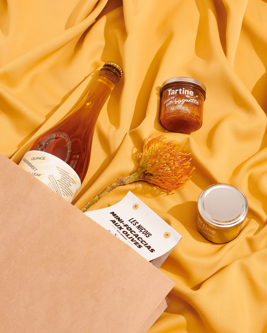 Feinkost-Produkte und Geschenkideen auf gelbem Stoff – Gourmie Goods.