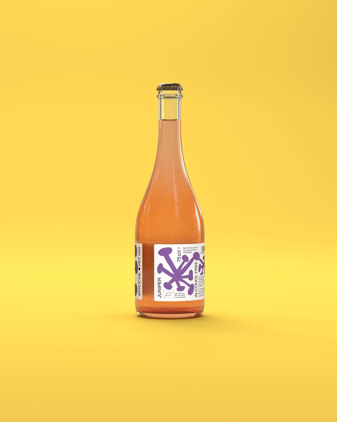 Flasche Juniper Pet Nat Kombucha von Bouche vor gelbem Hintergrund, das Getränk ist leicht orange und im Vordergrund.