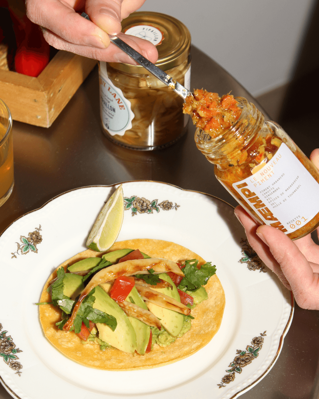 Eine Person gibt MAEMPI-Chili-Püree auf einen Taco mit Avocados und Pilzen.