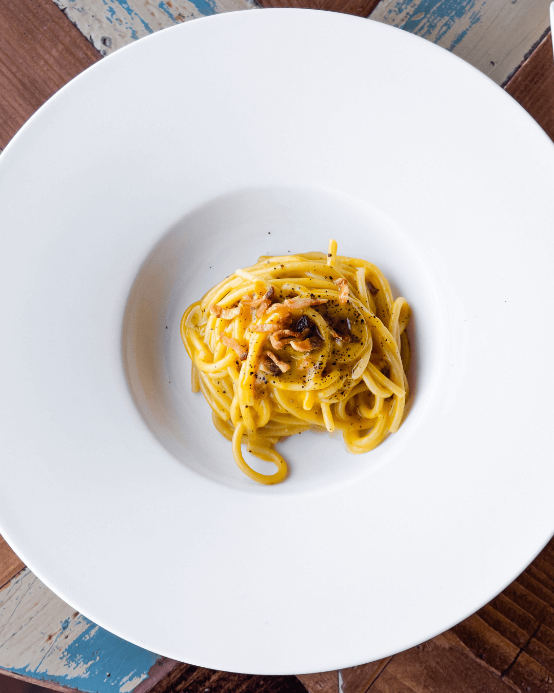 Spaghetti in cremiger Sauce mit Pfeffer und knusprigen Zwiebeln serviert.
