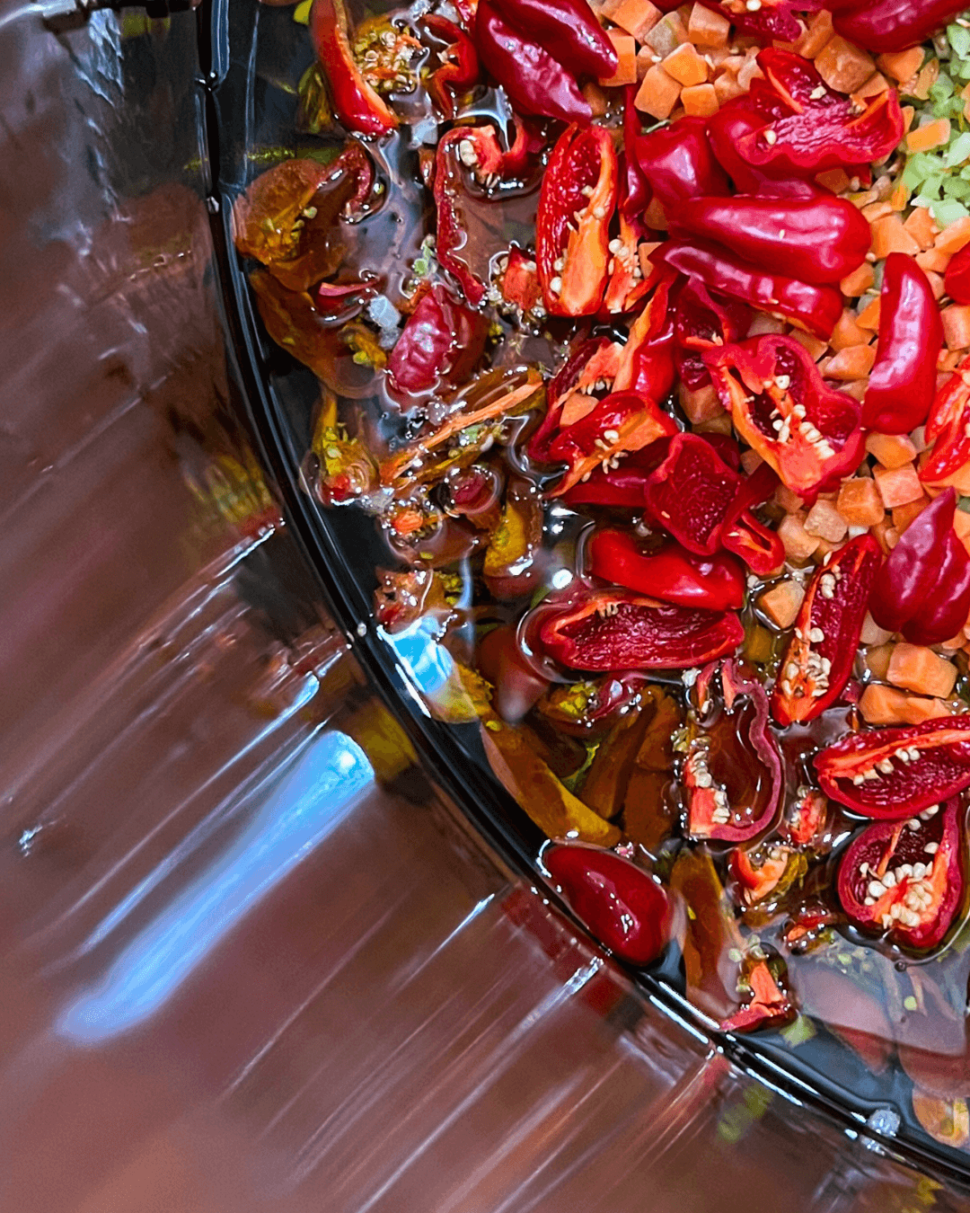 Geschnittene rote Chilis, Karotten und Zwiebeln in Flüssigkeit, vorbereitet für die Herstellung von Soße.